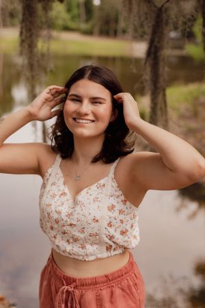Candid outdoor portrait by a lake wearing a floral crop top and coral shorts.