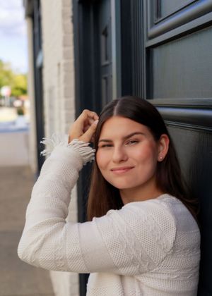 Person in a cozy white knit sweater posing against a dark background in a photo series.
