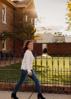 Lifestyle fashion photos showing movement against brick building and iron fence.