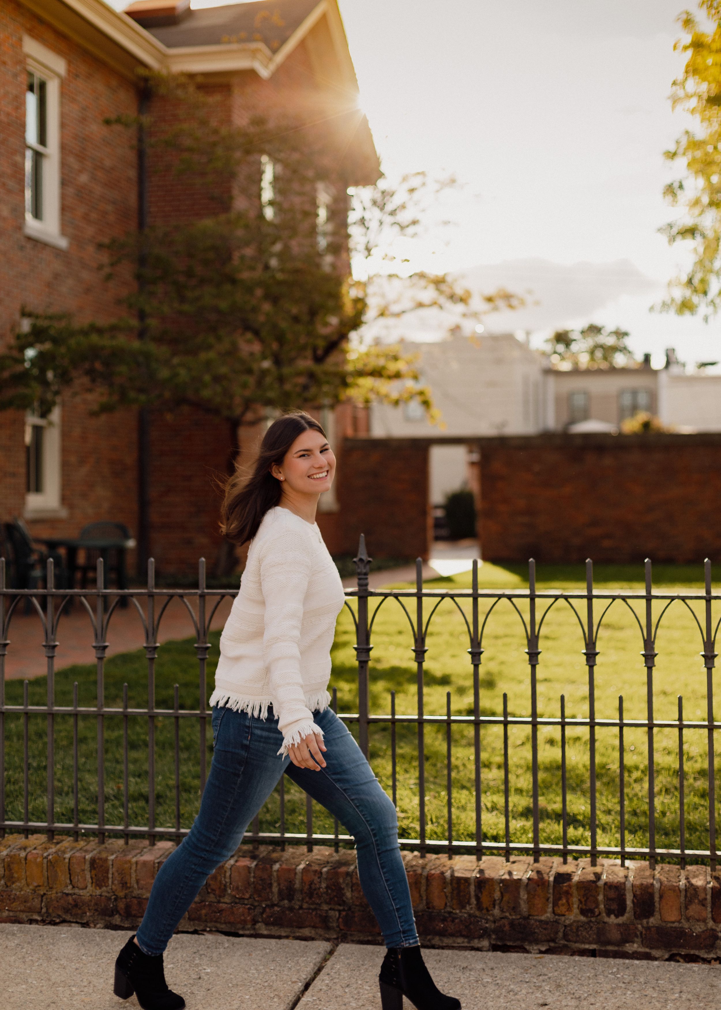 Lifestyle fashion photos showing movement against brick building and iron fence.