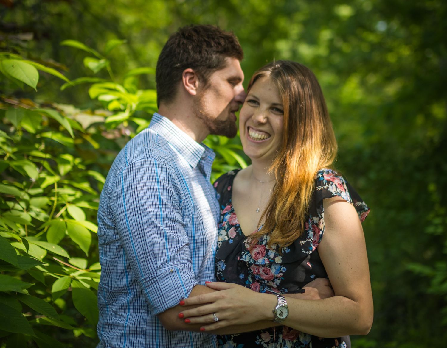 Couple sharing joyful laughter together in a sunlit garden.