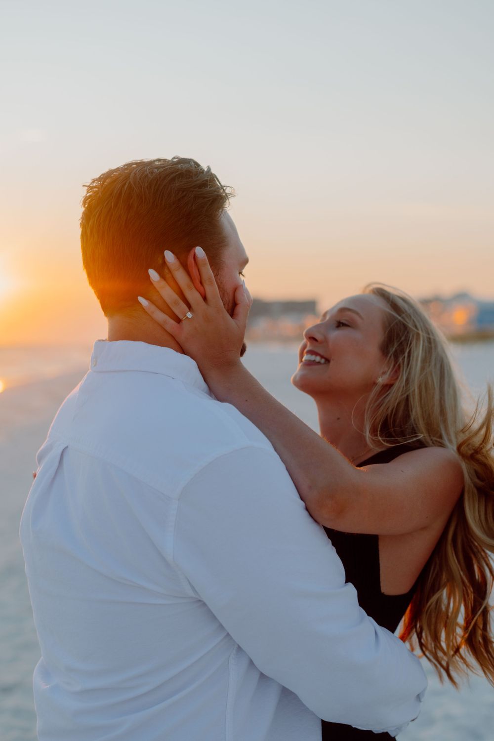 A romantic couple embraces on the beach during golden hour sunset.