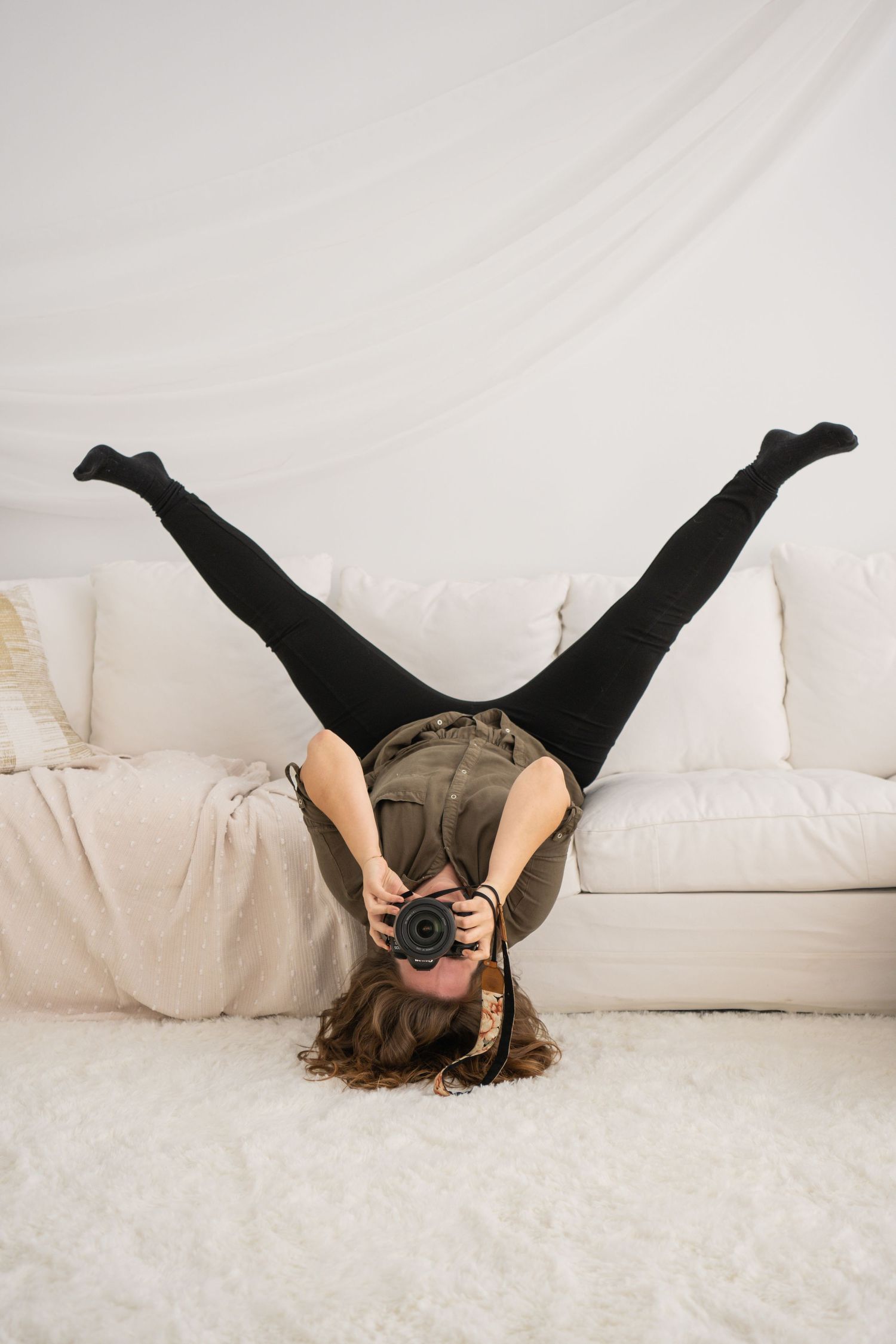 Creative upside down portrait on a white couch with a vintage camera.