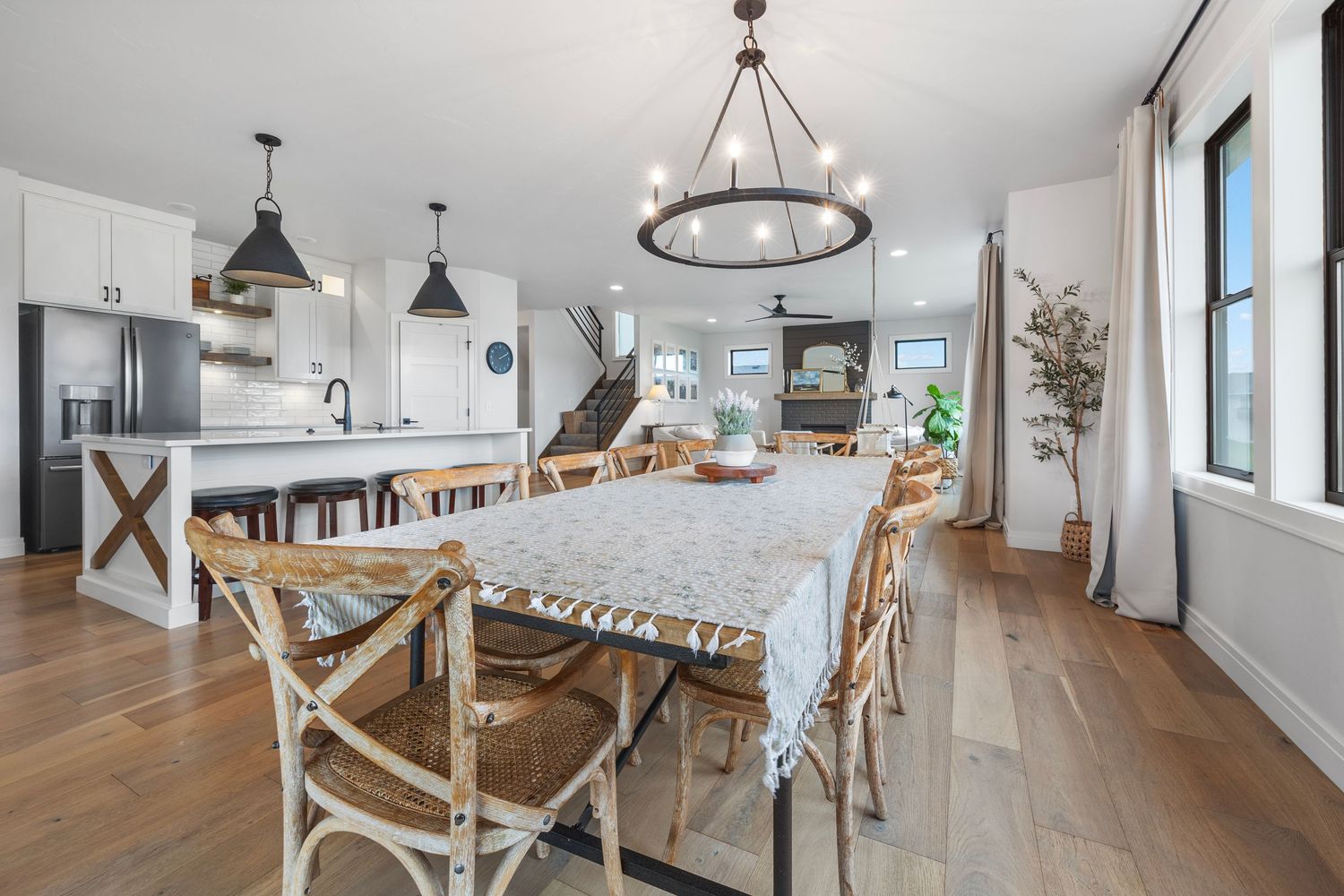Elegant dining area with chandelier, farmhouse table, and coastal views.