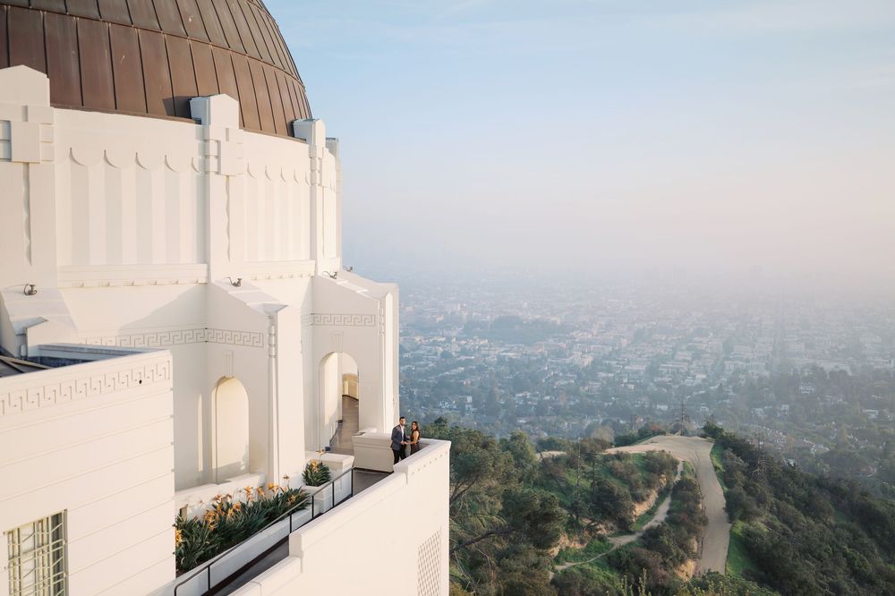 Aerial view of the iconic Griffith Observatory and Los Angeles cityscape on a hazy afternoon.