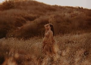 A couple embraces in a golden field of tall grass during sunset creating a romantic silhouette.