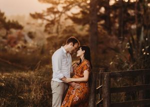 A romantic couple in fall clothing embraces during golden hour in a natural outdoor setting.