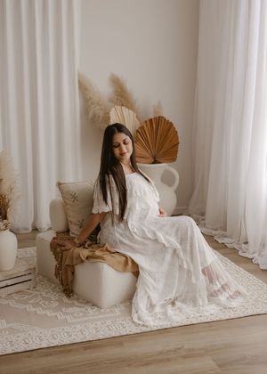 A woman in white flowing dress sits gracefully against pillars in different artistic poses across five connected photos.