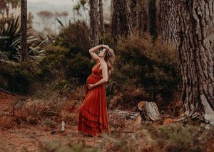 Person in flowing red dress dances gracefully through a moody forest setting during autumn.