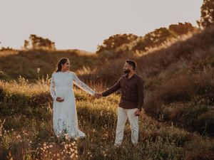 A couple walks hand in hand through a golden field at sunset creating a romantic silhouette against the warm sky.