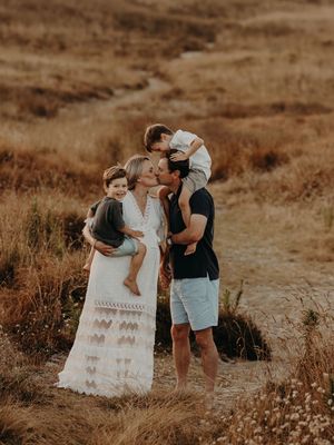 Intimate family portrait captured in golden hour light on rustic hillside path.