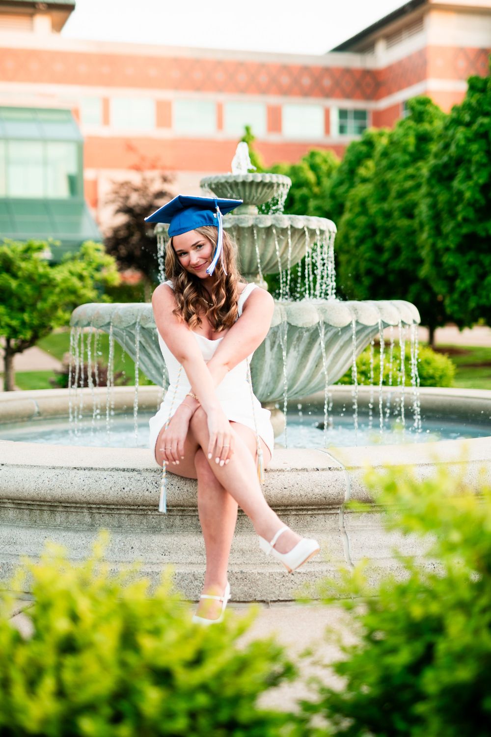 A dancer in pink leotard performs graceful poses by a fountain in a garden setting.