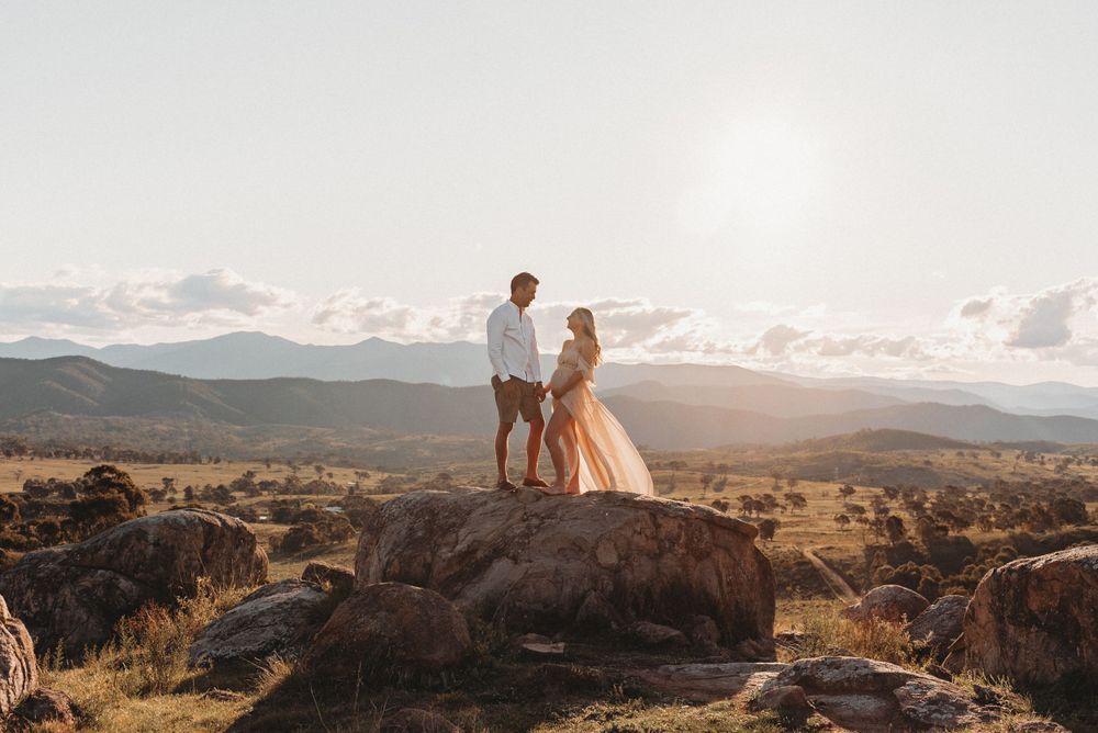 Romantic moment captured on rocky overlook with mountain vista at sunset.