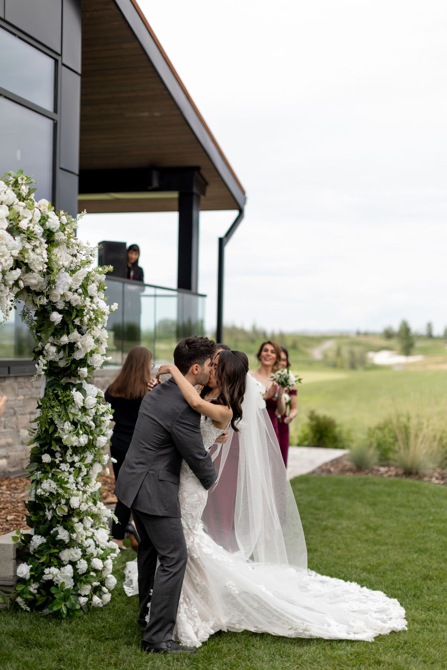 Wedding ceremony setup with elegant white floral arrangements and modern architecture.