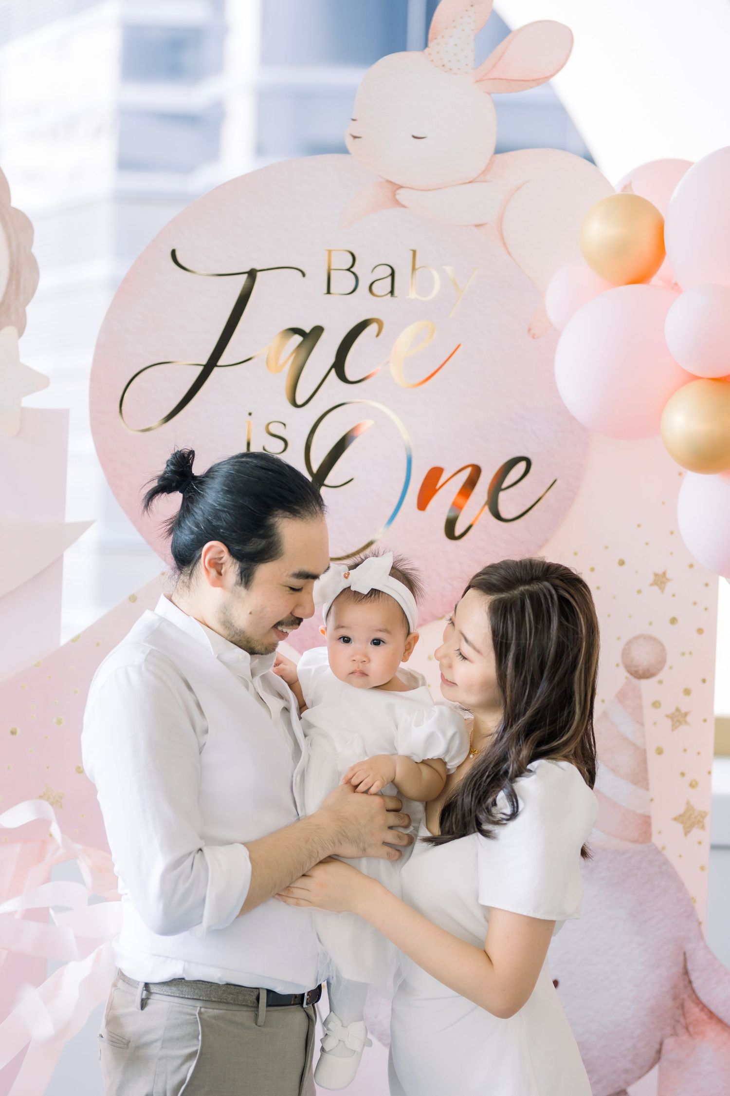 Baby celebration with blue and white balloon decor and cake display.
