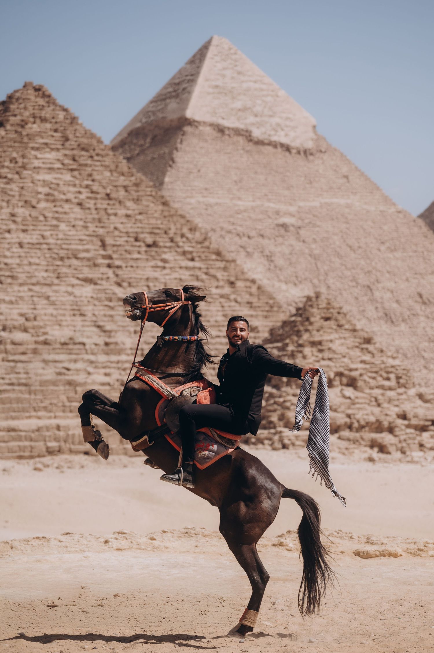 A sequence showing a horse rider performing dramatic tricks in front of the ancient Egyptian pyramids in the desert.
