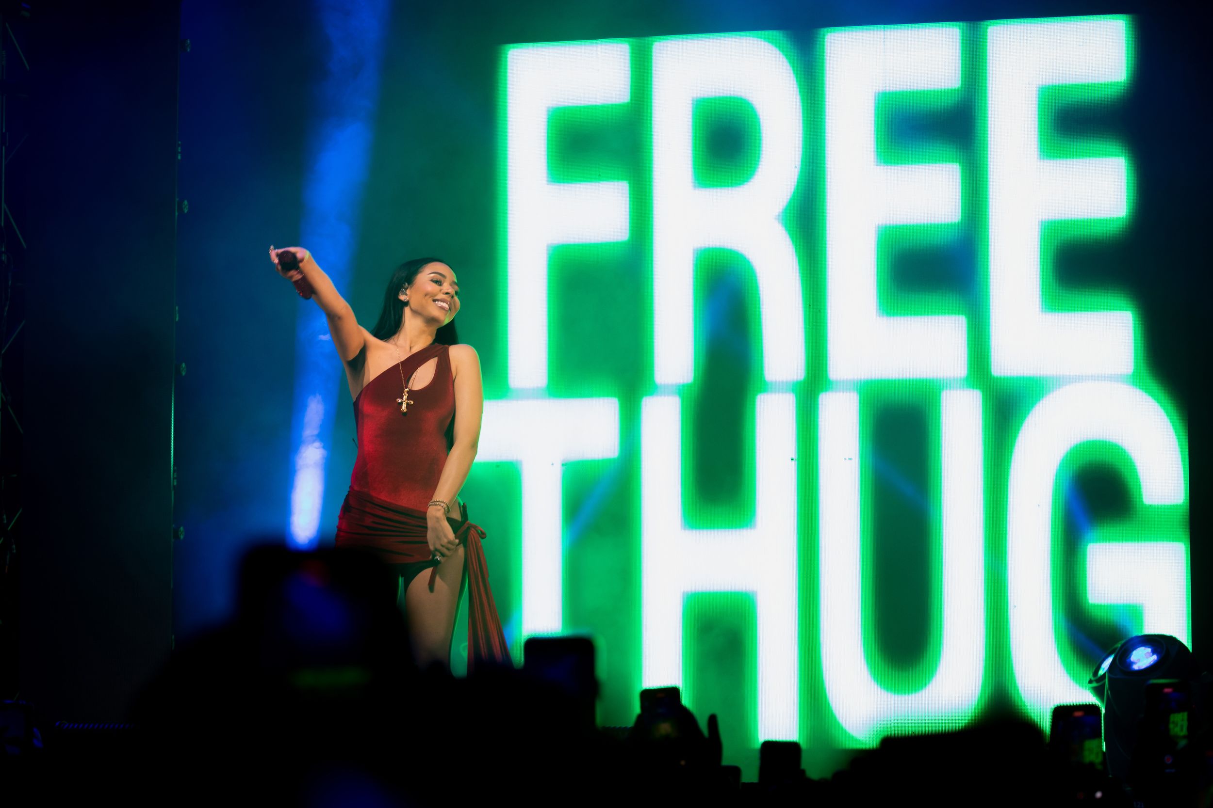Concert performance with green neon 'FREE THUG' sign illuminated on stage.