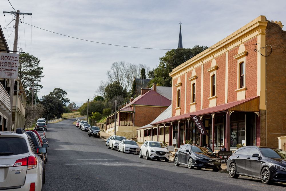 Lifestyle image of Carcoar village's Main Street lined with historic red brick buildings. Photo by Em Callaghan Photography.