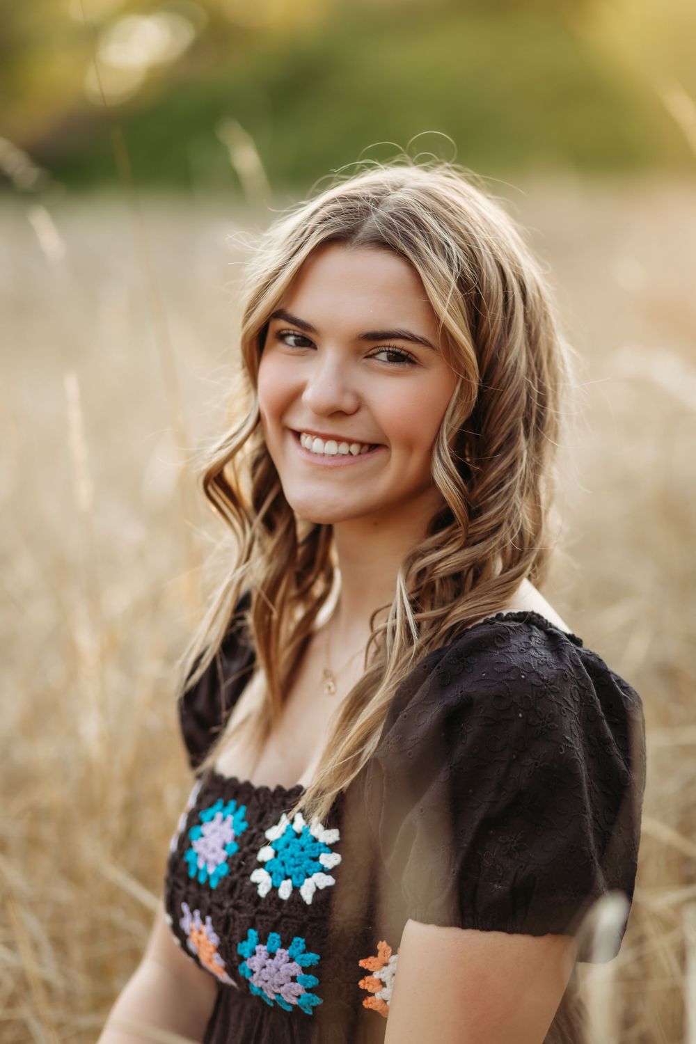 A beautiful embroidered folk dress is worn in a golden wheat field at sunset.