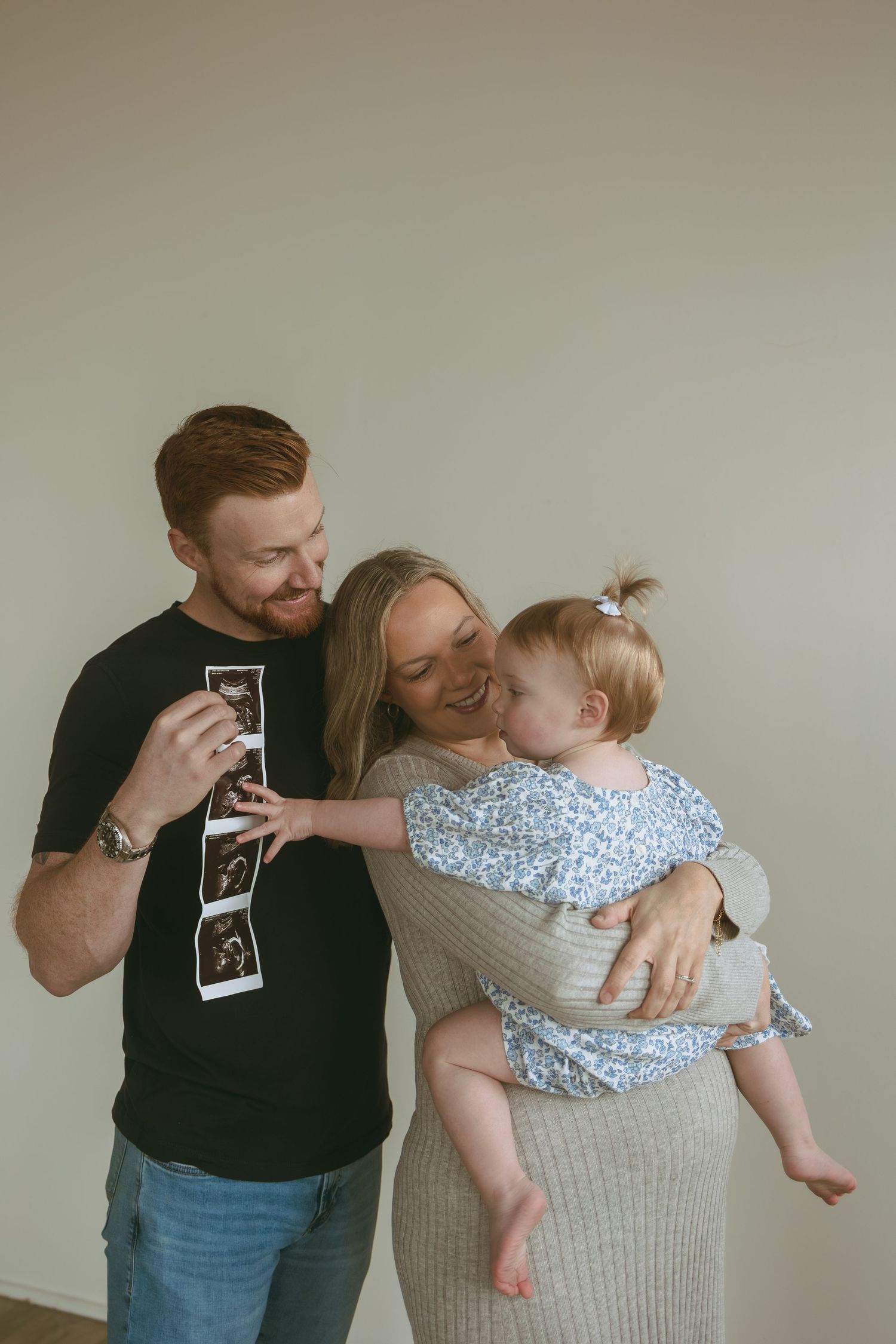 A couple holding a sonogram photo while embracing and sharing joyful reactions in a sequence of connected images.