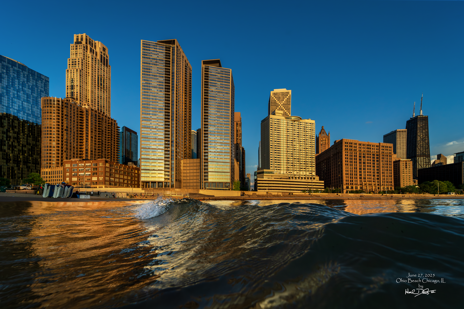 A dramatic view of Chicago's downtown skyscrapers reflecting a golden sunrise sunlight with wave crashing along Lake Michigan's shore.