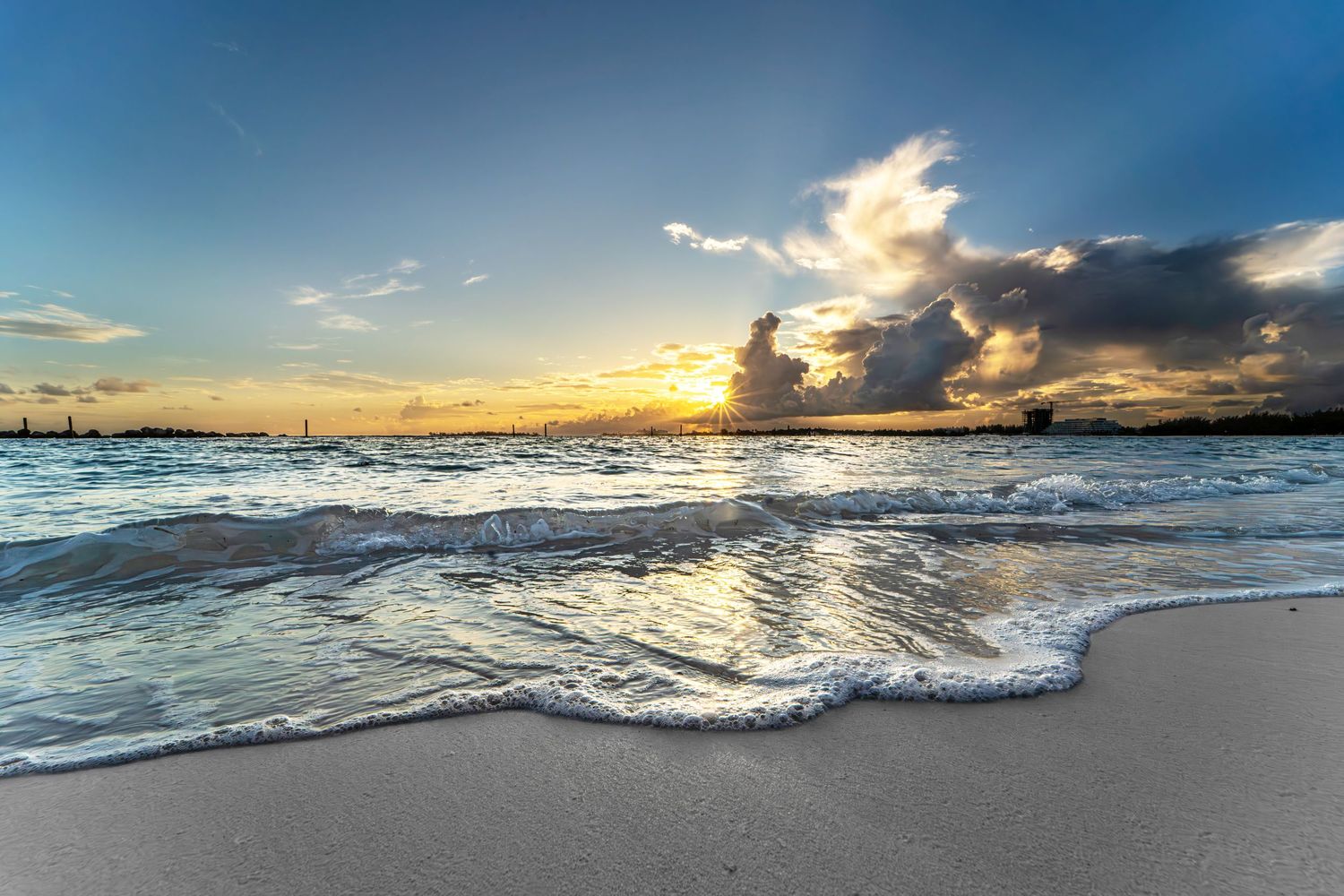 Sunrise at beach, golden hour, with water washing up on the sandy shoreline.