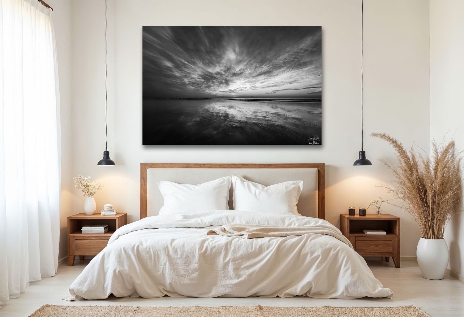 Minimalist white bedroom with dramatic black and white cloud photograph above bed and pendant lighting.