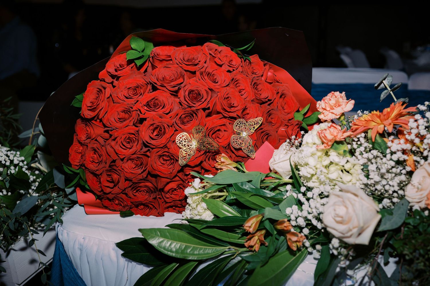 A stunning bouquet of red roses with pink roses and white baby's breath flowers on a blue surface.