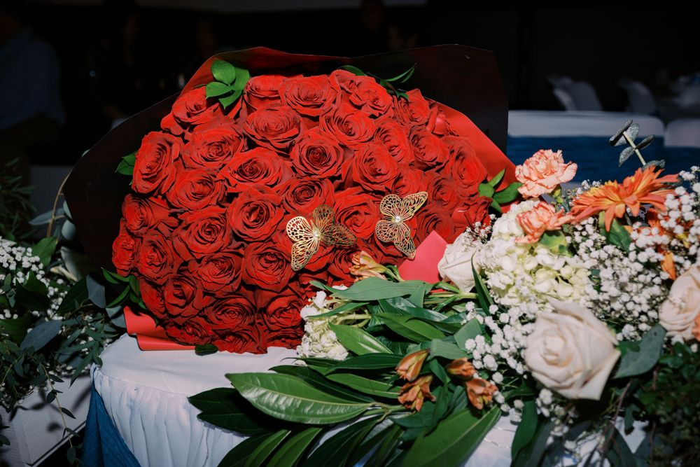 A stunning bouquet of red roses with pink roses and white baby's breath flowers on a blue surface.