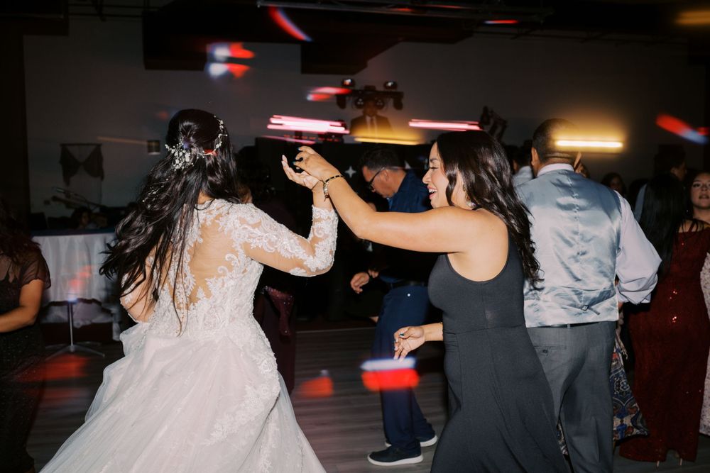 People dancing and celebrating at a wedding reception with a festive dark dance floor atmosphere.