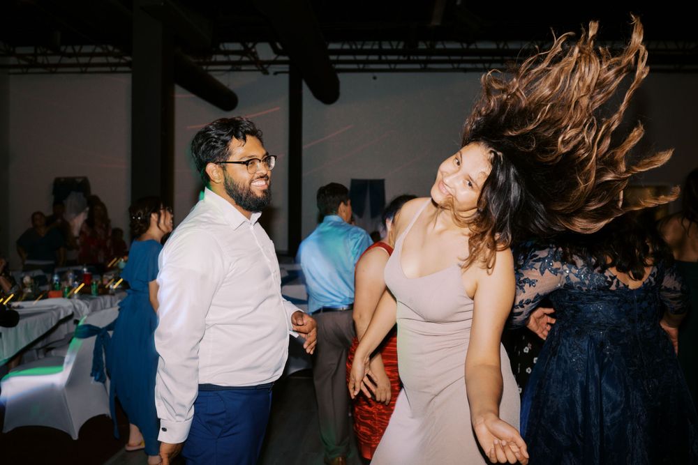 Woman in pink dress dancing energetically with hair flying at a wedding reception party.
