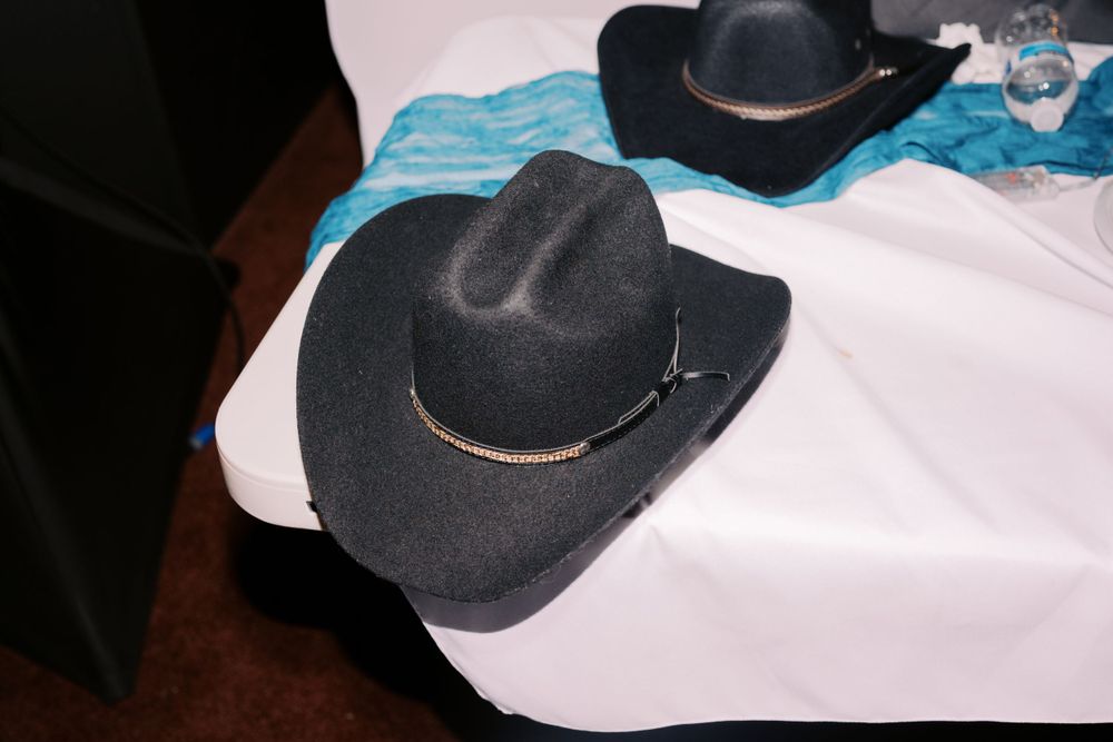 Two black cowboy hats with contrasting bands rest on a white surface in a dimly lit setting.