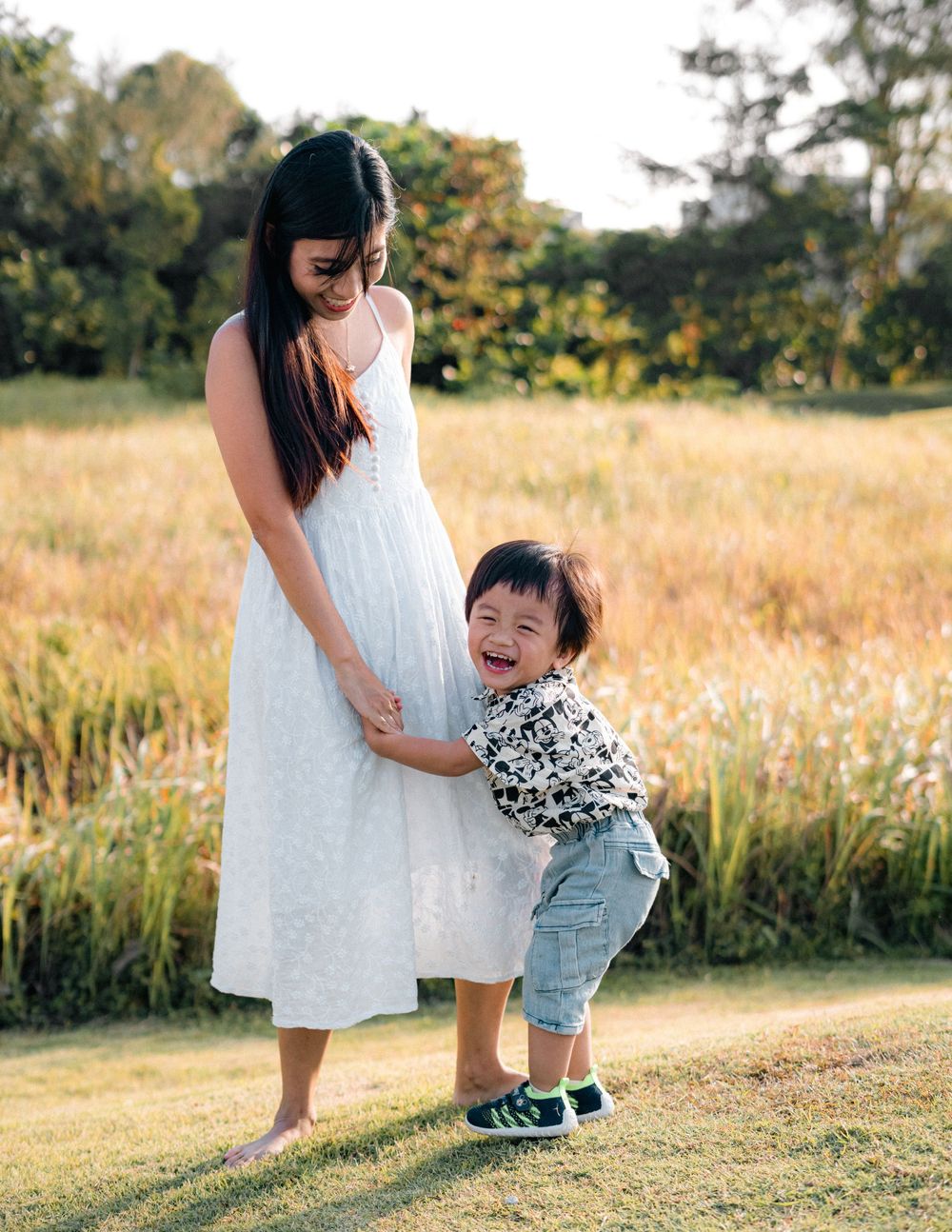 A tender moment between parent and child on a grassy field at sunset.