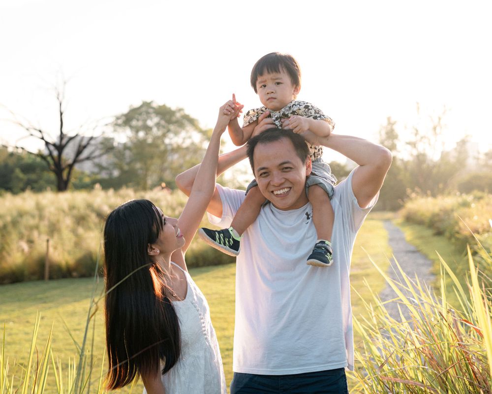 A happy family moment captured in golden sunlight amidst a natural grass field setting.