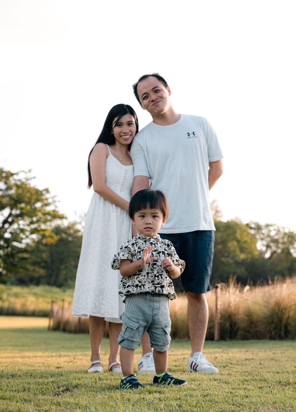 A family stands together on a grassy field during golden hour.
