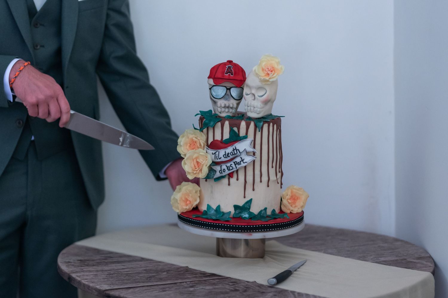 Modern wedding cake with decorative cartoon figures on top.