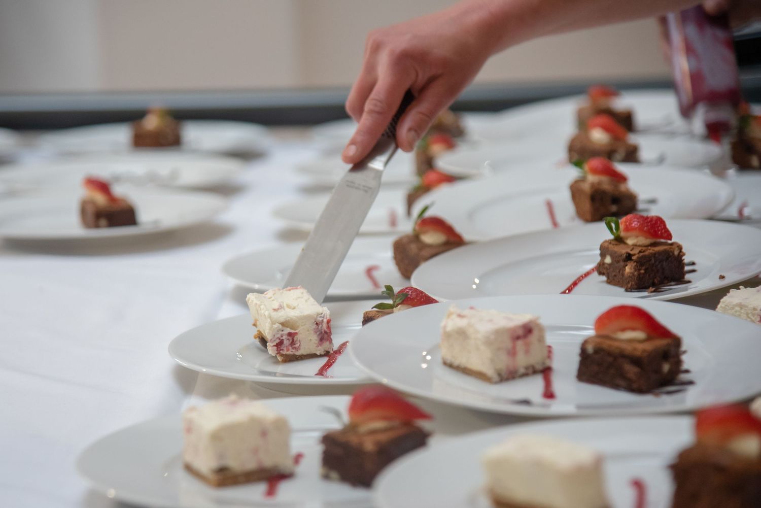 Elegant dessert plating with strawberries and chocolate garnishes on white tablecloth.