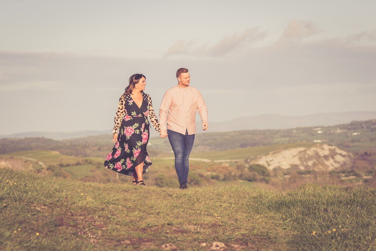 A portrait of a couple holding hands walking through the fields of the North Wales Coast. North Wales Portrait Photographer
