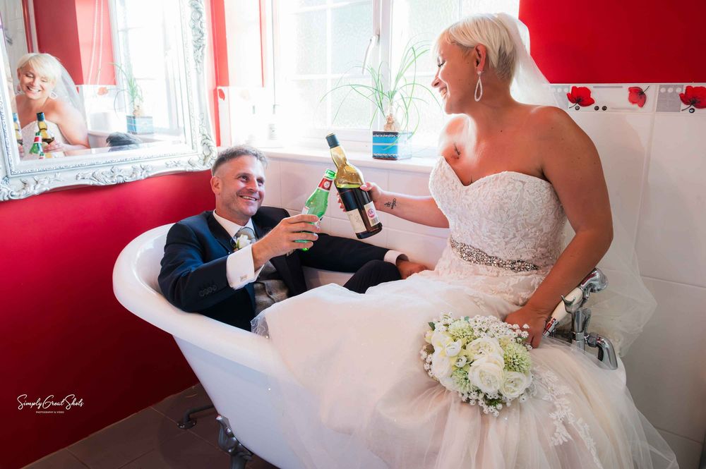Bride & groom toasting in a roll-top bath at Winter's Tale Country Barn, Buckinghamshire – candid wedding photo by SimplyGreatShots