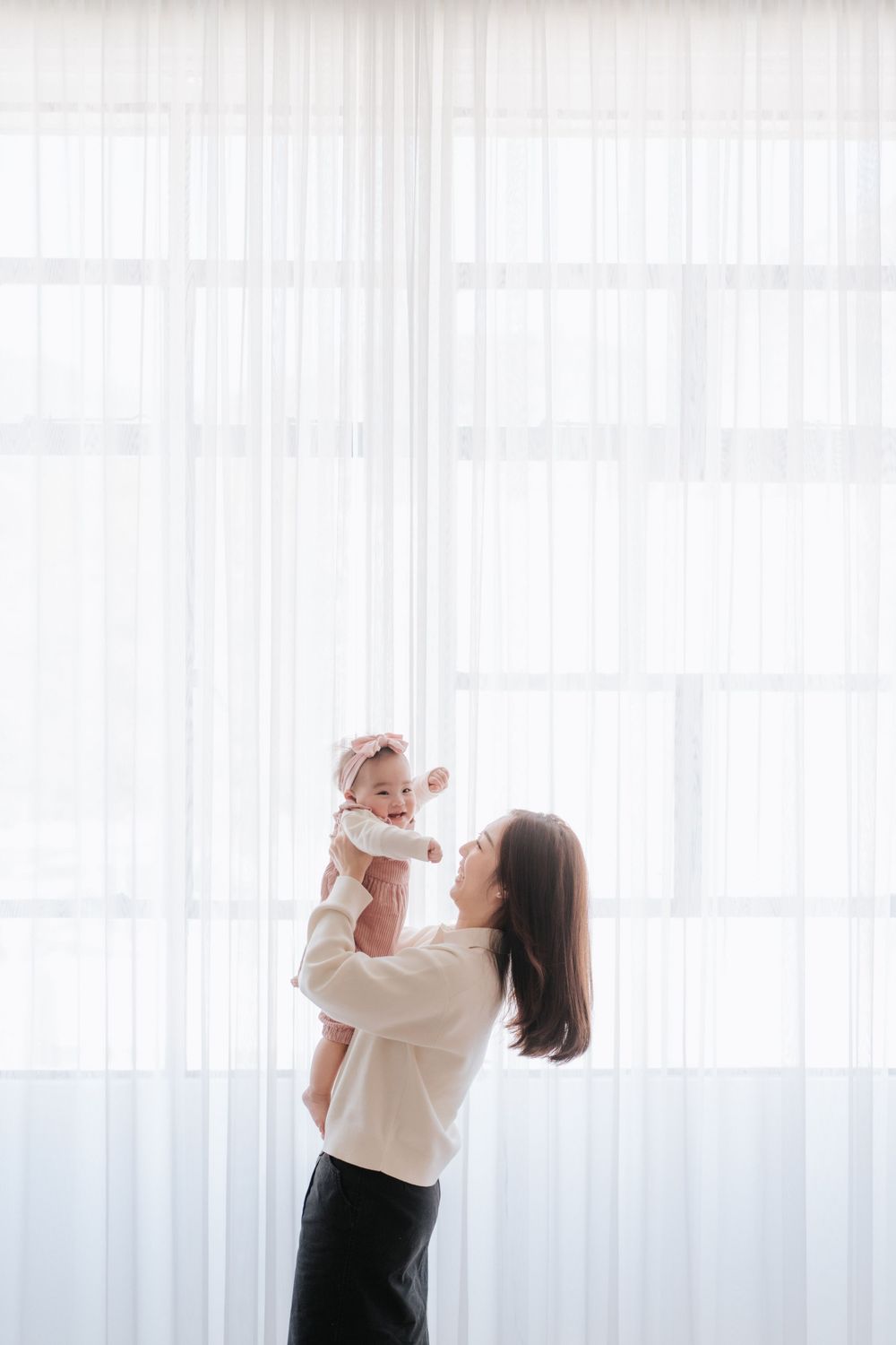 Intimate lifestyle portrait session with soft white curtain backdrop.