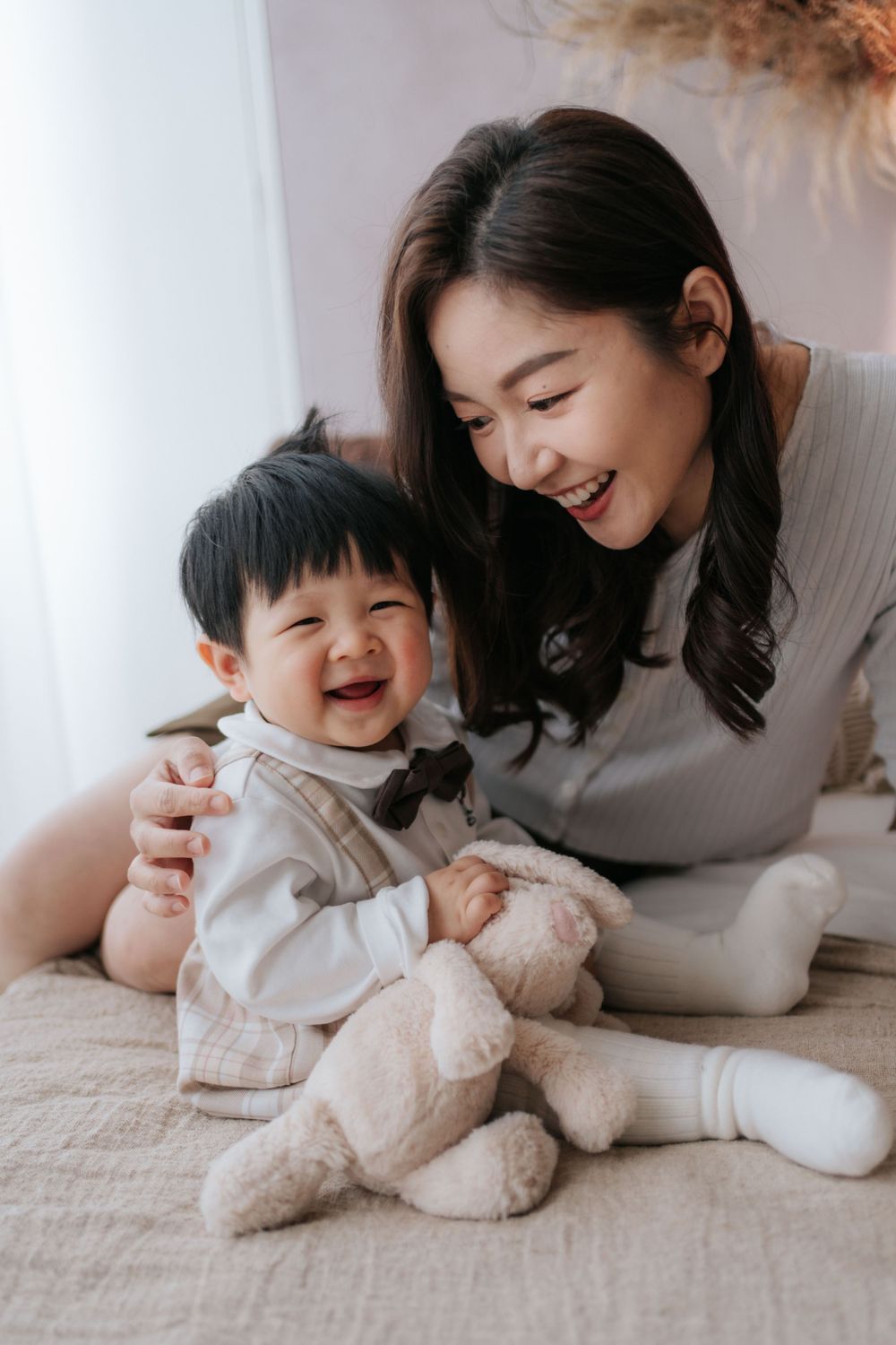A playful moment captured on a white bed with a stuffed animal teddy bear.