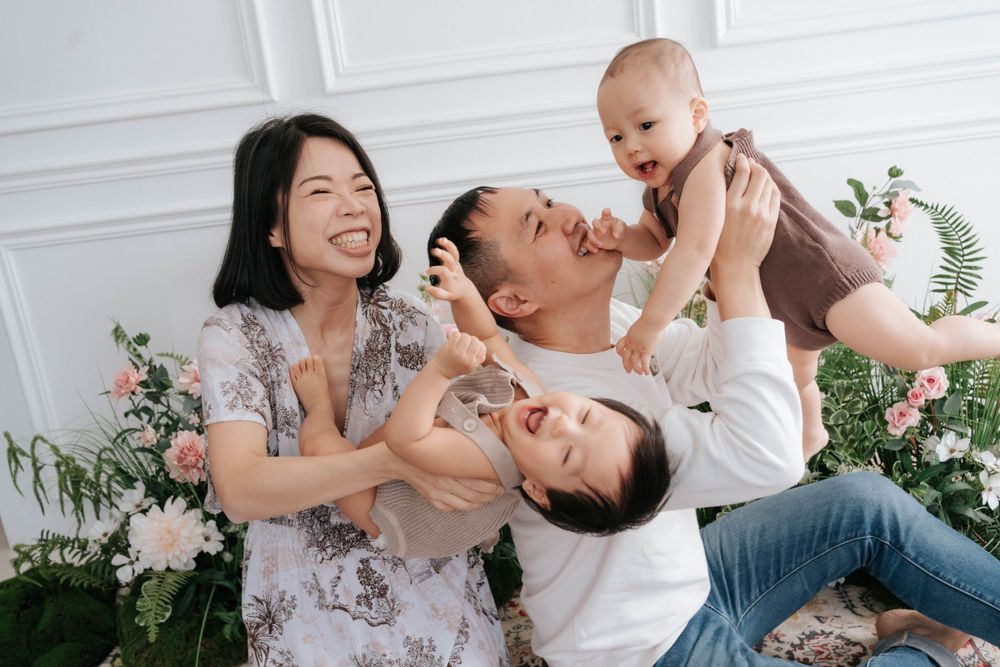 Joyful family photoshoot against white walls with floral decorations.