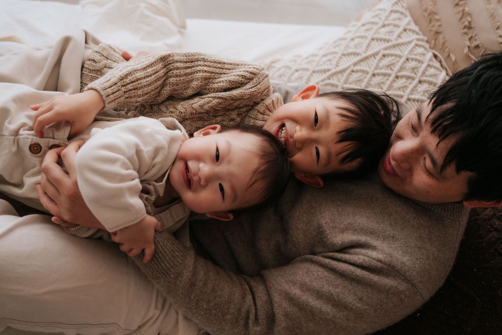 Intimate family moments captured on a comfortable bed with neutral tones.