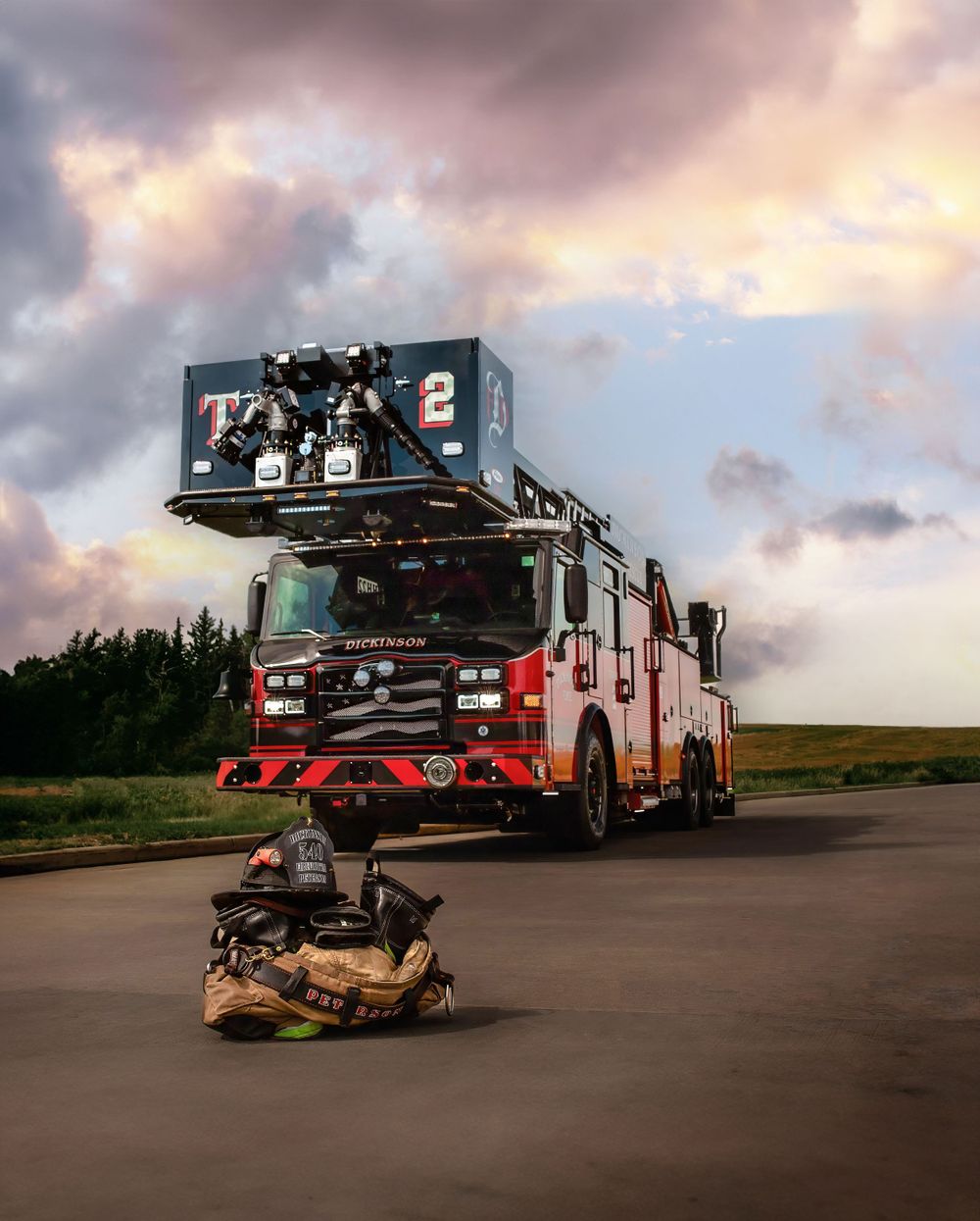 Dramatic sunset view of a red fire truck with firefighting equipment and gear laid out in front.