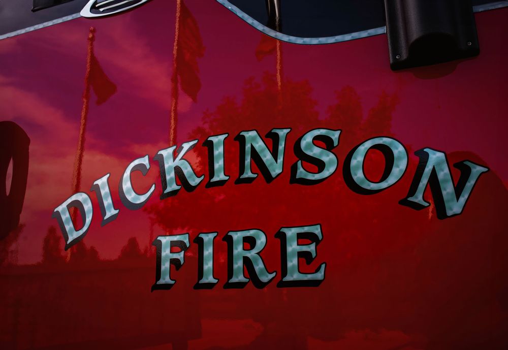 Close-up of 'DICKINSON FIRE' lettering on red fire truck exterior.