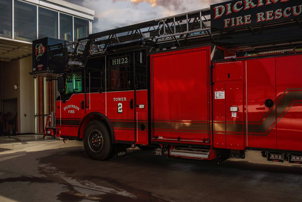 Side view of Dickinson Fire Rescue truck parked outside building entrance.