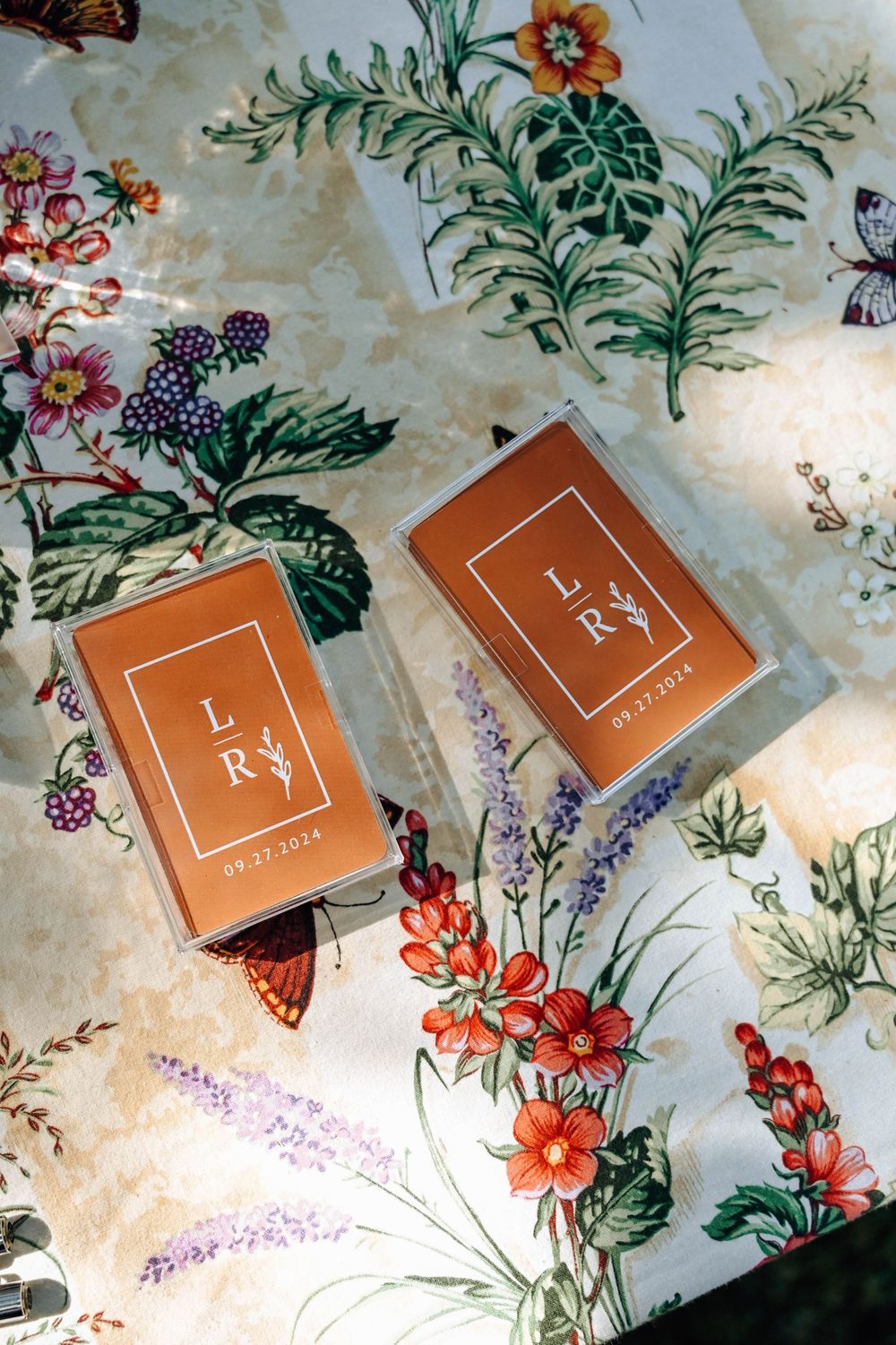 Two orange-brown LRY book or card boxes displayed on a vintage floral pattern fabric with butterflies and flowers.