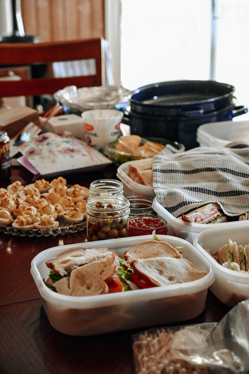 A buffet table spread with appetizers featuring various dips, breads, and snacks in white serving dishes.
