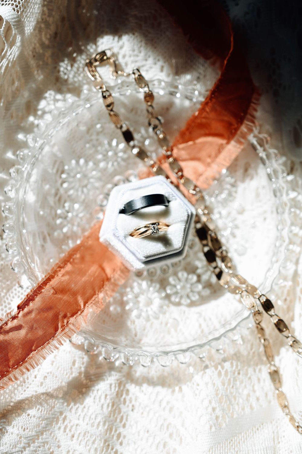 Water droplet with peach and white colors highlighting a small decorative metal button or charm set against a textured surface.