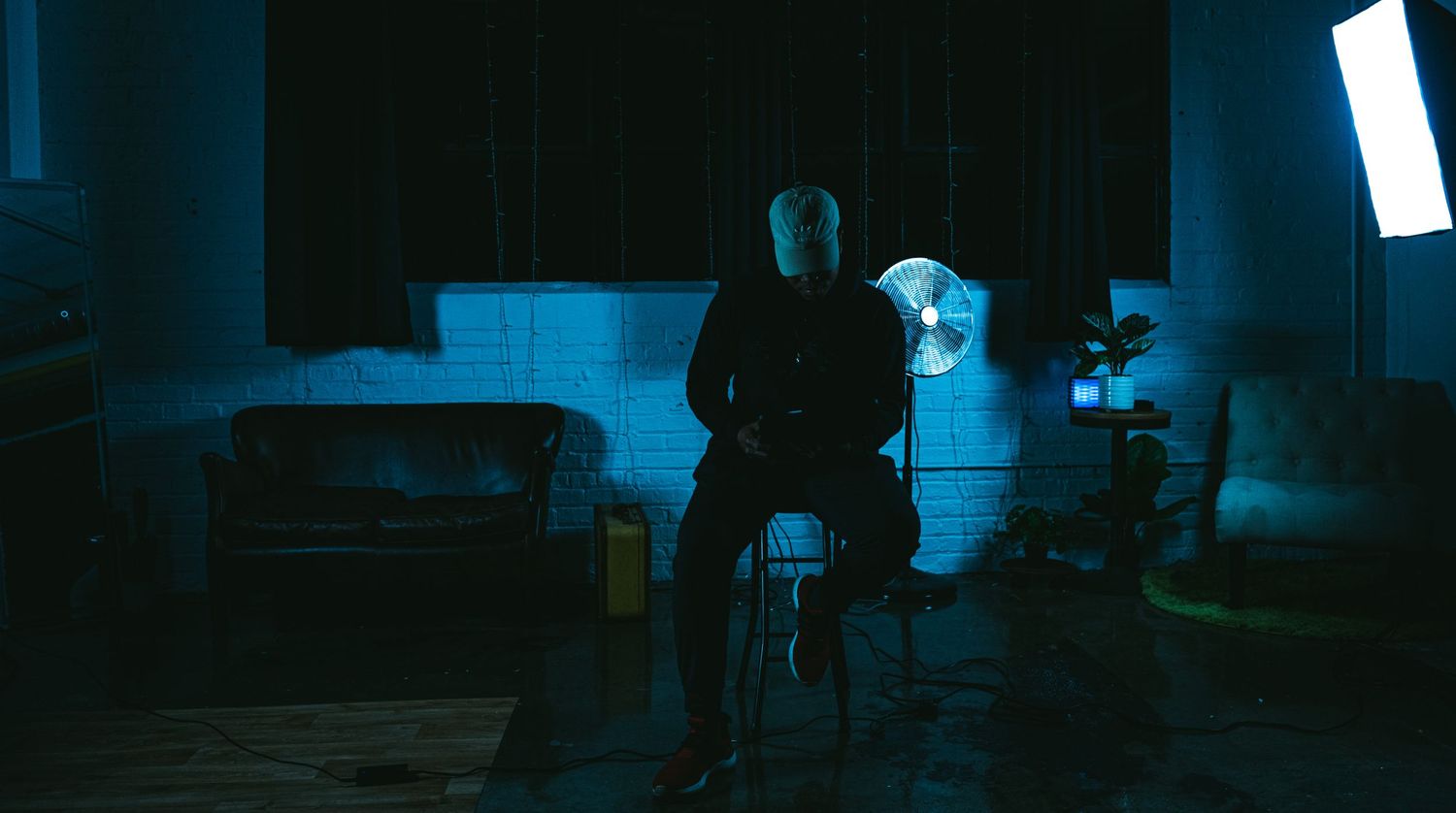 Silhouetted figure standing in dark room with blue ambient lighting.